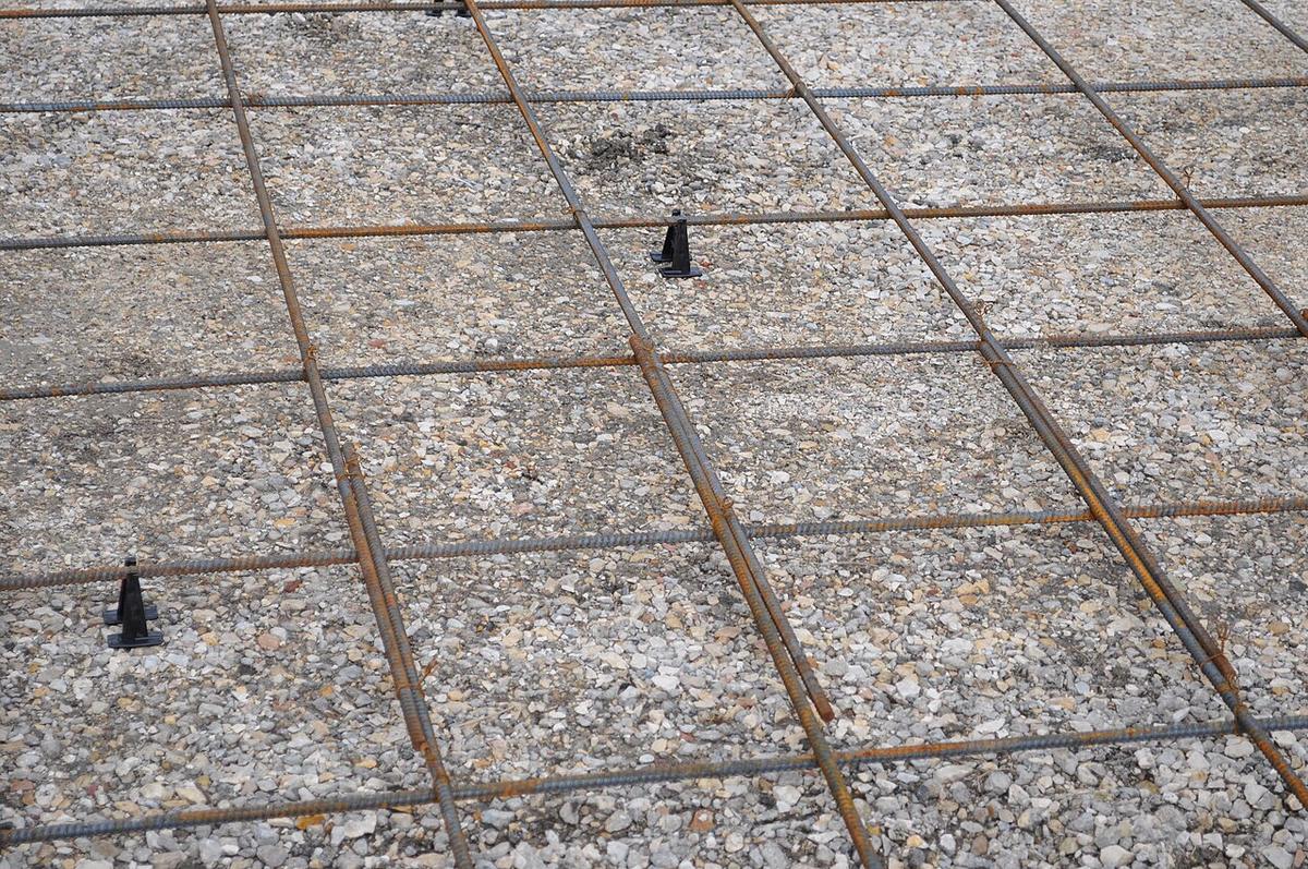 A rebar grid on plastic chairs over a gravel base, before a concrete pour